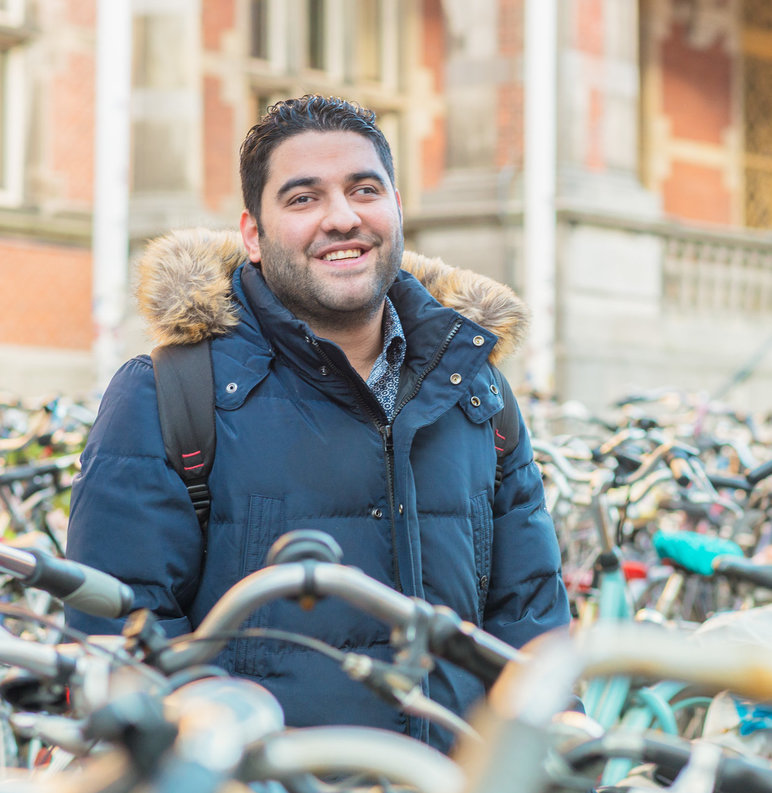 Foto van Yousef voor het academiegebouw, tussen de fietsen