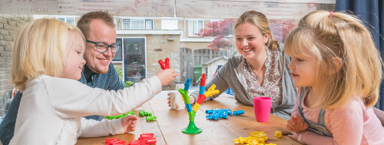 Foto van Wolter met zijn vrouw en twee dochters die een spelletje spelen aan tafel